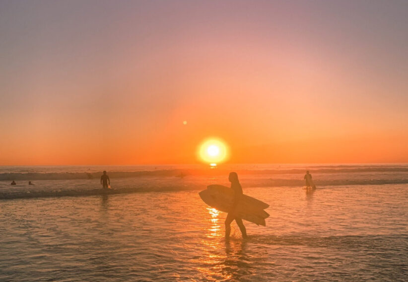 Surfer on a beach in California sunset