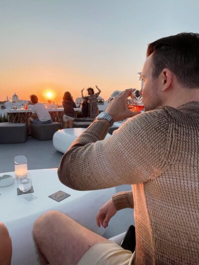 Marcell Rekasi CEO of Wanted For Nothing web design agency enjoying a drink at a rooftop bar while looking at the sunset
