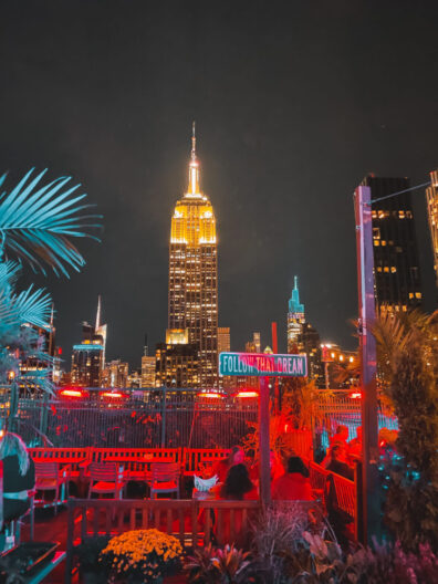 New York City rooftop bar at night with Empire State Building in the background