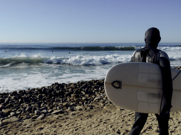 Surfer with surfboard and wetsuit at Santa Barbara beach