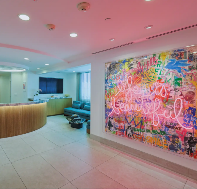 The reception area at Gramercy Center, featuring a vibrant neon sign artwork that reads 'Life is Beautiful,' creating a welcoming and modern ambiance.